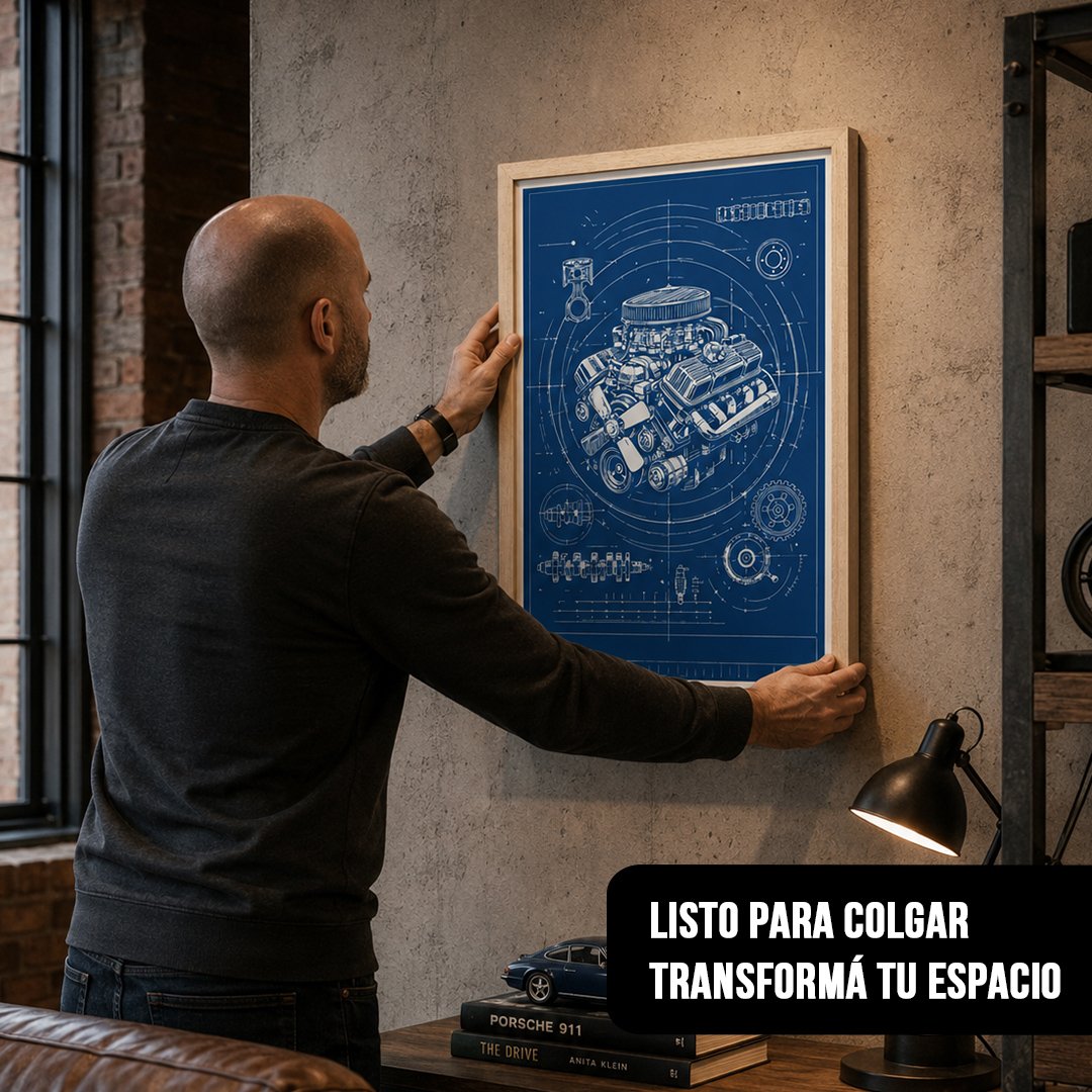 Hombre de espaldas colocando un cuadro vertical de plano blueprint de motor azul en marco de madera clara sobre pared de cemento gris