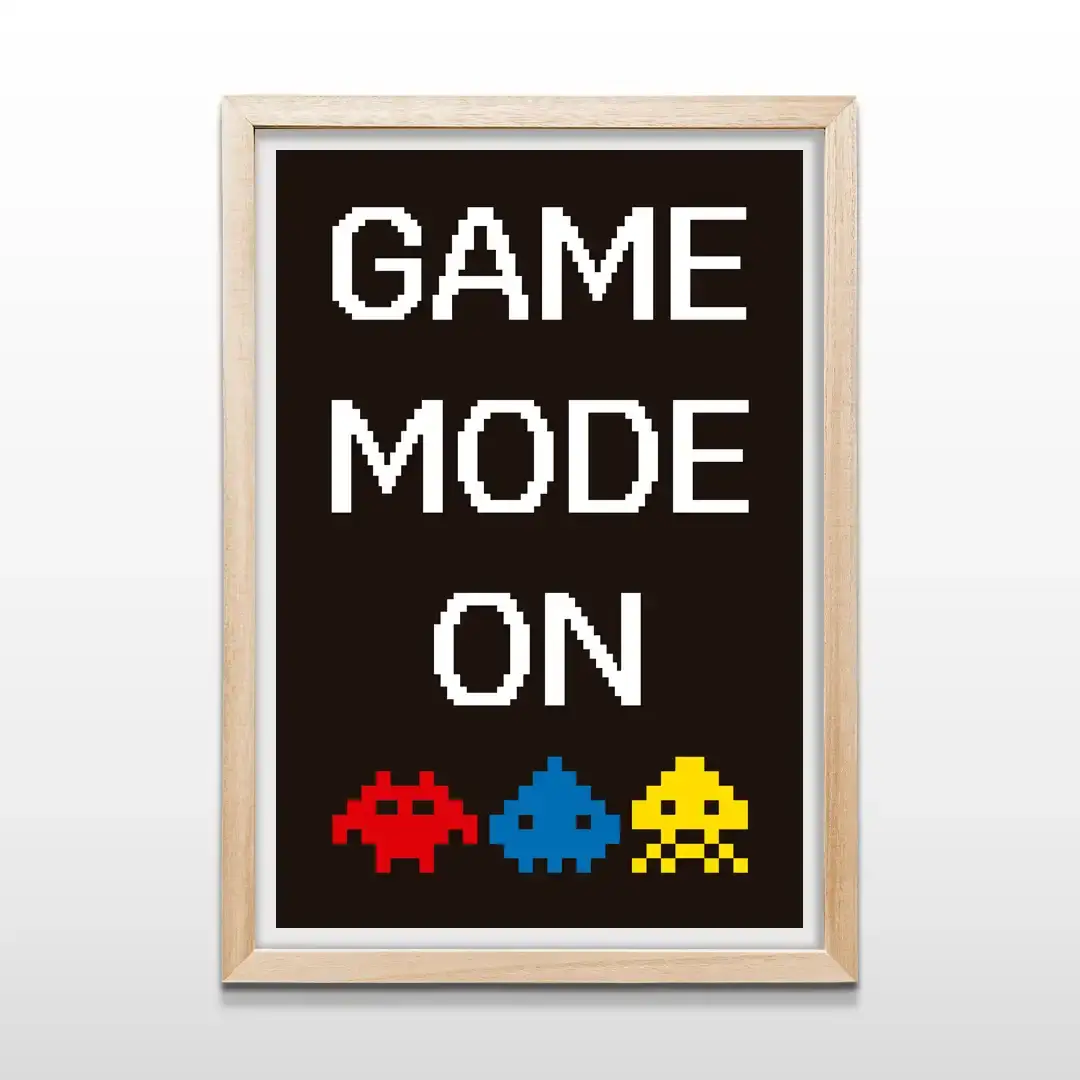 Cuadro decorativo Game Mode On con texto pixelado blanco y monstruos arcade de 8 bits sobre fondo oscuro con marco de madera clara, lámina artística retro para paredes de dormitorios
