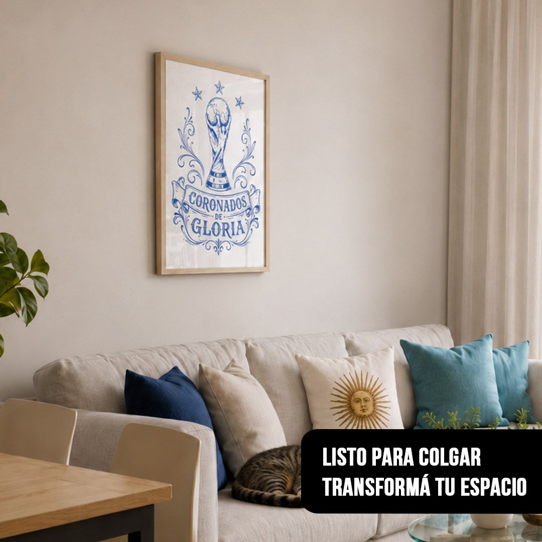 Cuadro vertical enmarcado en madera clara con ilustración azul de la Copa del Mundo, tres estrellas y la frase "CORONADOS DE GLORIA", colgado sobre un sillón claro donde duerme un gato