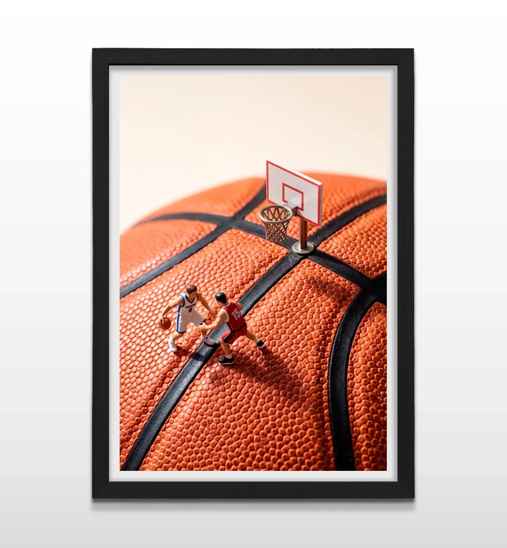 Cuadro vertical en marco negro con lámina fotográfica creativa de partido de básquetbol en miniatura sobre pelota naranja